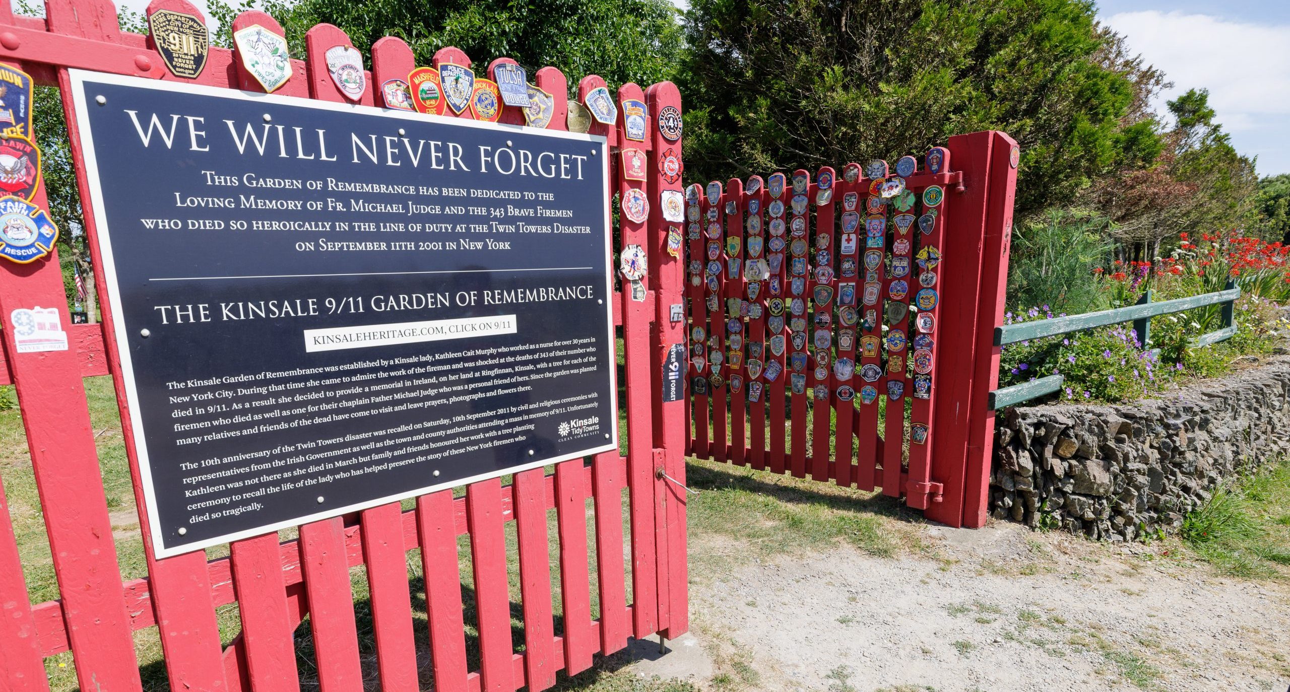 A framed poster displaying grid photo portraits of 343 FDNY members who died on September 11, 2001, framed in dark wood next to an American flag.
